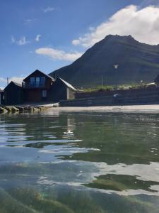 a body of water with a mountain in the background at visitHOMES Faroe Islands in Leirvík