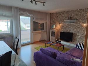 a living room with a purple couch and a brick wall at Ferienwohnung Schleiten in Püttlingen