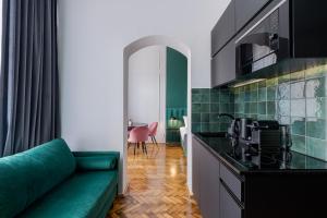 ein Wohnzimmer mit einem grünen Sofa und einer Küche in der Unterkunft Wawel Boutique Residence - Krakow Old Town in Krakau