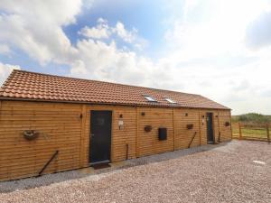 a wooden building with two doors and a fence at Sanderlings Cottage in Mablethorpe