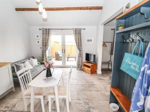 a kitchen and living room with a white table and chairs at Wagtail Cottage in Mablethorpe