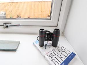 a book and two binoculars on a window sill at Wagtail Cottage in Mablethorpe