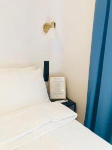 a bed with white sheets and a clock on a side table at Supreme Apartment in the City Center in Kraków