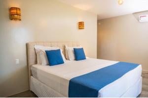 een slaapkamer met een bed met blauwe en witte kussens bij Villa Zen Hotel in Camocim