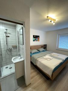 a bedroom with a bed and a shower and a sink at Apartments and rooms pri Bašlju in Cerkno