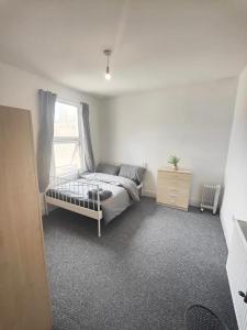 1 dormitorio con cama y ventana en Lovely 3 bedroom serviced apartment in Leytonstone, en Londres