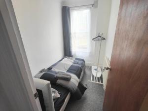 a small bedroom with a bed and a window at Lovely 3 bedroom serviced apartment in Leytonstone in London
