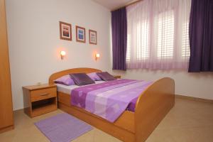 a bedroom with a wooden bed with purple sheets at Apartments by the sea Slano, Dubrovnik - 8608 in Slano