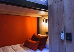 a bedroom with an orange wall and a bed with pillows at Faz Hostel in Cordoba