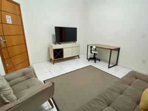 uma sala de estar com um sofá, uma secretária e uma televisão em Área Central/3 quartos/grande grupos em Marília