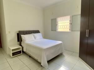 um quarto com uma cama com lençóis brancos e uma janela em Área Central/3 quartos/grande grupos em Marília