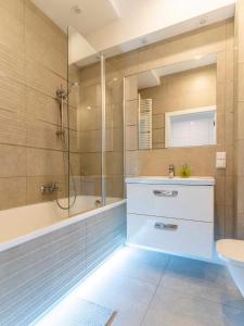 La salle de bains est pourvue d'une baignoire, d'un lavabo et d'une douche. dans l'établissement FIRST -- Green Żoliborz Apartment 4, à Varsovie
