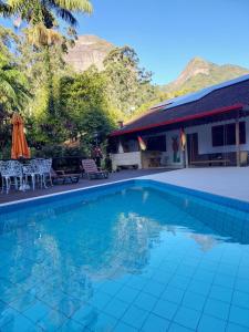 a swimming pool in front of a house at Lumiar Eco Lodge - Casa Alemã in Nova Friburgo