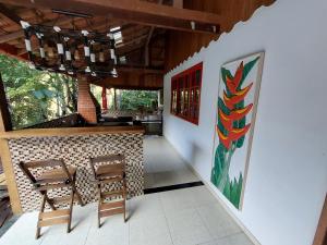 a patio with a table and chairs and a painting on the wall at Lumiar Eco Lodge - Casa Alemã in Nova Friburgo