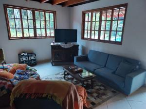 a living room with a couch and a tv at Lumiar Eco Lodge - Casa Alemã in Nova Friburgo