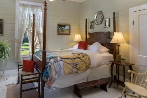 a bedroom with a bed and a chair and a window at Maison D'Memoire Bed & Breakfast Cottages in Rayne