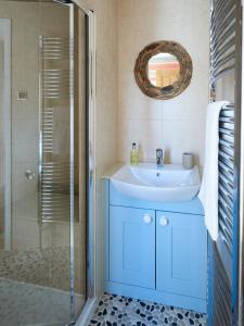 ein Badezimmer mit blauem Waschbecken und Dusche in der Unterkunft Magenta - A stunning Seafront house with lovely and uninterrupted Beach Views - Aldeburgh Coastal Cottages in Aldeburgh + 5 Fotos