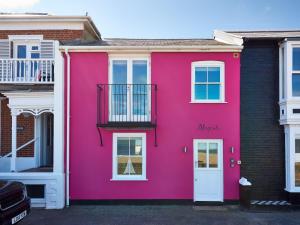 ein rosa Haus mit einer weißen Tür in der Unterkunft Magenta - A stunning Seafront house with lovely and uninterrupted Beach Views - Aldeburgh Coastal Cottages in Aldeburgh