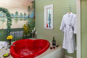 uma banheira vermelha numa casa de banho verde com um roupão branco em Maison D'Memoire Bed & Breakfast Cottages em Rayne