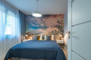 a bedroom with a blue bed with a painting on the wall at Apartament Widok 1 in Piechowice
