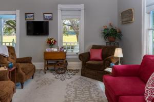 a living room with couches chairs and a tv at Maison D'Memoire Bed & Breakfast Cottages in Rayne