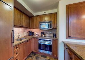 Kuchnia z drewnianymi szafkami, zlewem i kuchenką mikrofalową w obiekcie Everline Resort & Spa Rentals by TO w mieście Olympic Valley