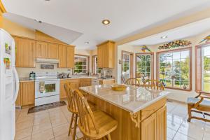 a kitchen with wooden cabinets and a large island with chairs at House Of Serenity in East Wenatchee
