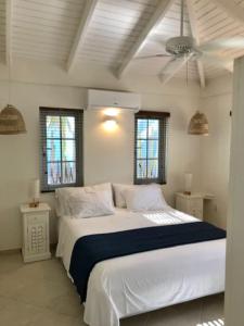 a bedroom with a large white bed with a ceiling fan at Villa Perla due (diving villa Chikitu) in Kralendijk