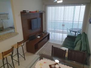 a living room with a green couch and a television at AP Praia do Forte! Charme e conforto!(104) in Cabo Frio