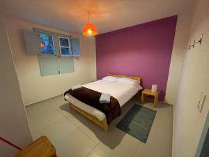 um quarto com uma cama com uma parede roxa em Casita Azul em Salento