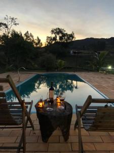 a table with a bottle of wine and candles next to a pool at Pousada Chales da Canastra in Vargem Bonita