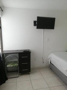 sypialnia z łóżkiem i komodą z telewizorem w obiekcie CASA VERDE Habitaciones en Bucaramanga w mieście Bucaramanga
