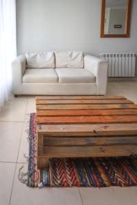 sala de estar con sofá blanco y mesa de centro de madera en Departamento de un dormitorio - CRESPO en Santa Fe