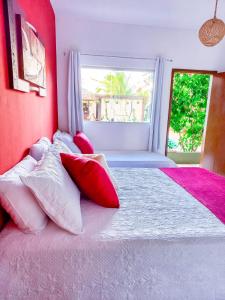 een slaapkamer met een groot bed met rode en witte kussens bij Pousada Primavera in São Miguel do Gostoso