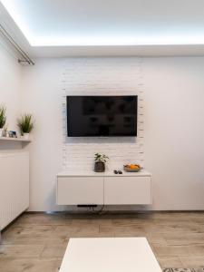 a white living room with a tv on a white brick wall at FIRST -- Green Żoliborz Apartment 5 in Warsaw