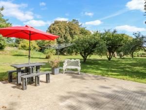 a picnic table with a red umbrella and a bench at Beehive Cottage in Kilbrittain