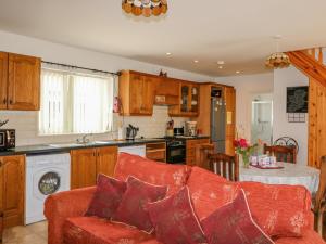 a living room with a red couch in a kitchen at Beehive Cottage in Kilbrittain