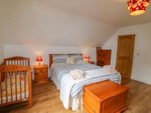 a bedroom with a bed and two night stands and a crib at Beehive Cottage in Kilbrittain