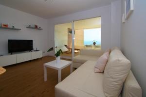ein Wohnzimmer mit einem weißen Sofa und einem Fernseher in der Unterkunft APARTMENT BY THE SEA CALACEITE in Torrox Costa