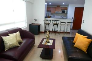 een woonkamer met 2 leren banken en een tafel bij Ecusuites TorreSol I Parking Trade Center - Gye Airport in Guayaquil