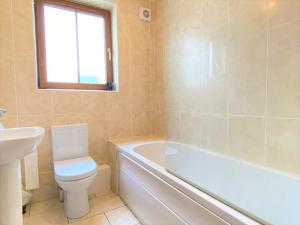 a bathroom with a toilet and a tub and a sink at Brooklands Central Apartment in Newcastle