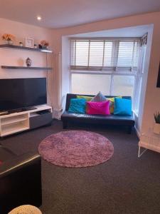 a living room with a couch with colorful pillows at Beachside House in Brighton & Hove +4 photos
