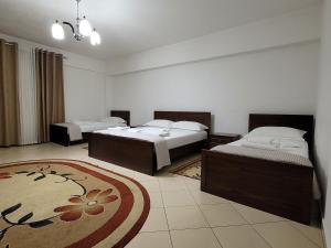 1 dormitorio con 2 camas y alfombra en Hotel Taverna Zisi, en Ersekë