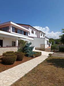 a large white house with a pathway in front of it at Hotel Holiday in Poreč