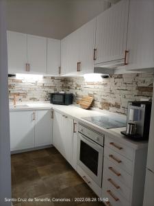 a white kitchen with white cabinets and appliances at Schöne Wohnung in Puerto de la Cruz mit Garten. in Puerto de la Cruz