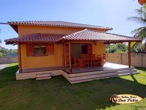 ein kleines gelbes Haus mit einer Veranda und Stühlen in der Unterkunft Bahia Haus Don Pietro in Canavieiras