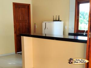 a kitchen with a counter top with a refrigerator at Bahia Haus Don Pietro in Canavieiras