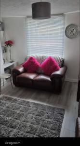 a brown leather couch in a living room with a clock at Modern Single room for rental in Colchester Town Centre! in Colchester
