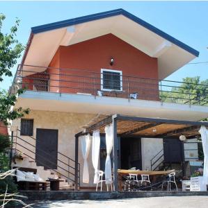 a house with a balcony and a table and chairs at La terra dei ciliegi tra l'Etna e il mare di Taormina in Piedimonte Etneo
