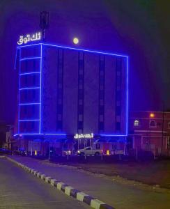 un gran edificio con luces azules por la noche en أرائك توق, en Sakaka